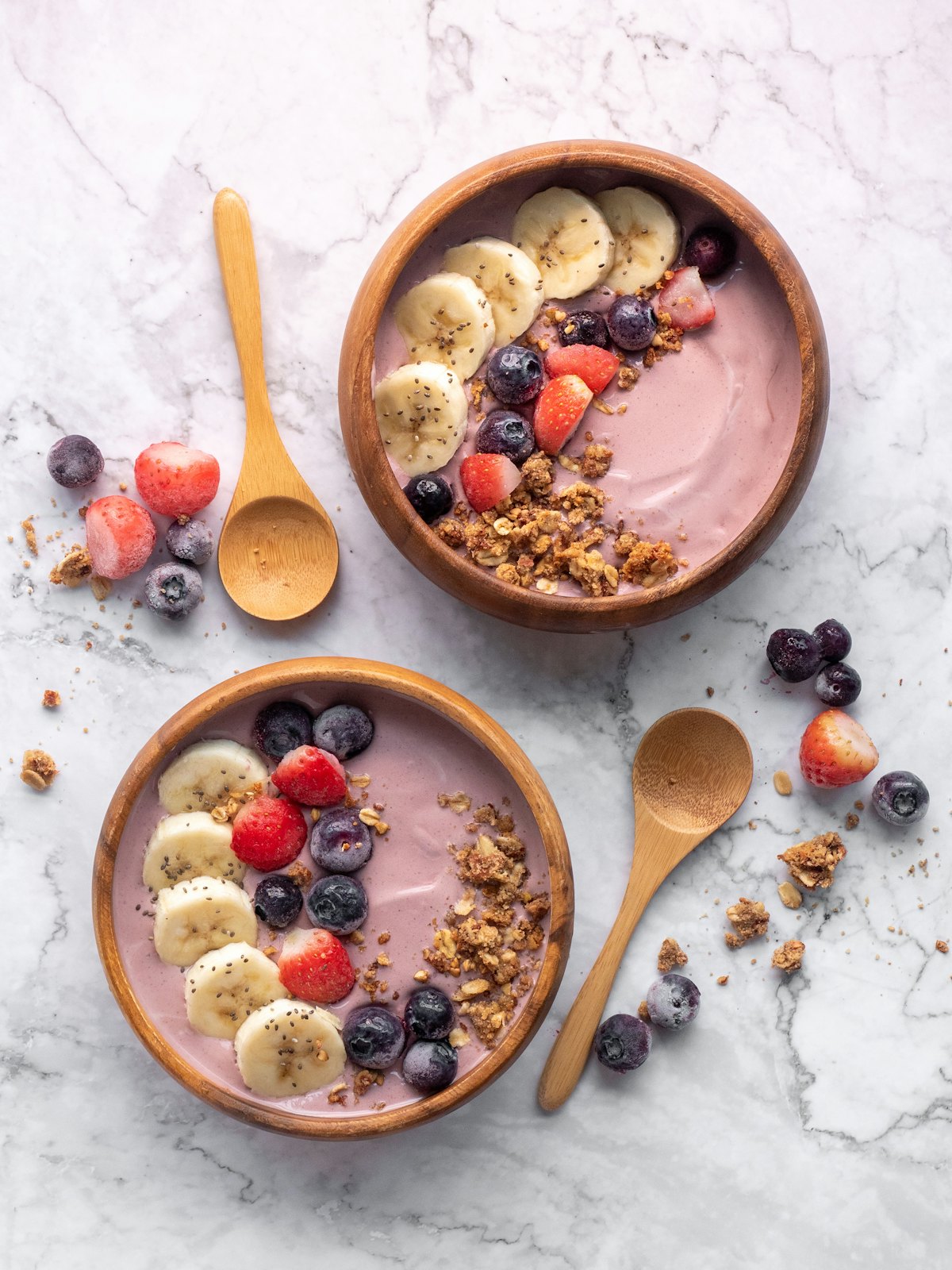 Dos açaí bowls cremosos con plátano, fresa, arándanos y granola